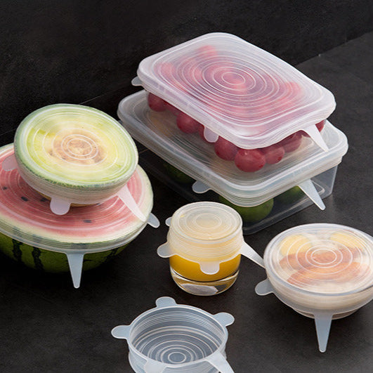 Silicone food covers in various shapes on a dark surface