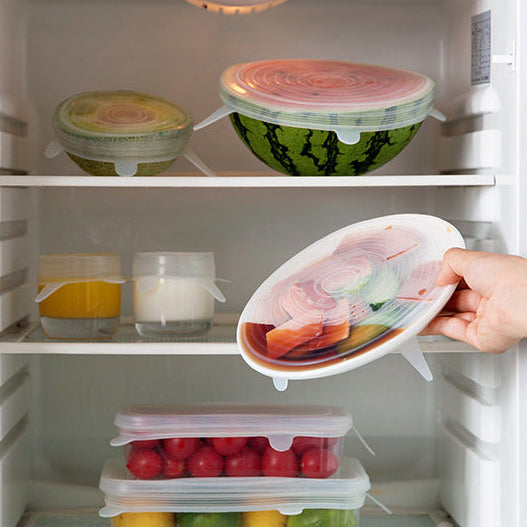 Refrigerator with food containers and a hand holding a silicone lid.