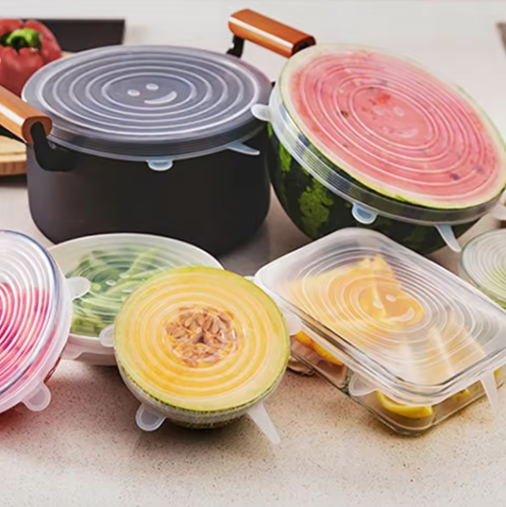 Silicone food covers on various fruits and vegetables on a kitchen counter.